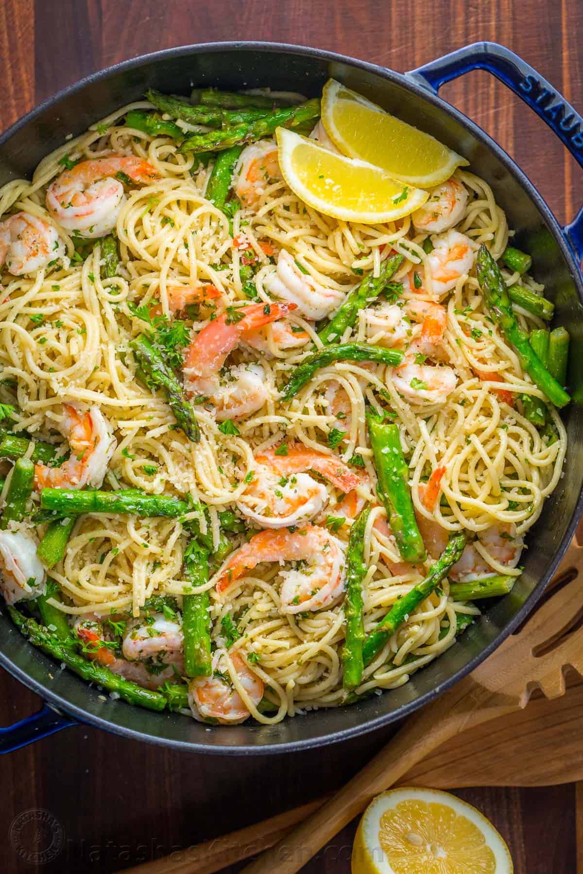 Shrimp Scampi Pasta with asparagus in a pan garnished with lemon wedges